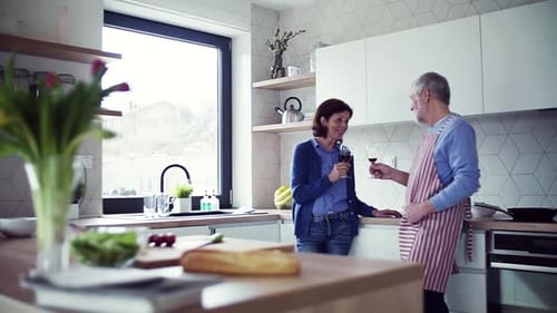 Affectionate senior couple sharing wine in a kitchen