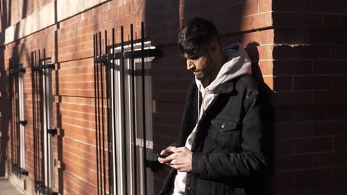 Young Man Using Smart Phone Outside Sunny Brick Building Adult