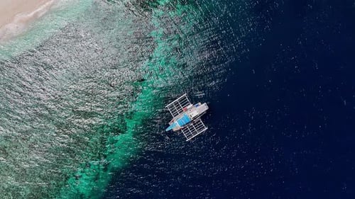 Top-down drone footage of a boat in deep blue water in the Philippines.