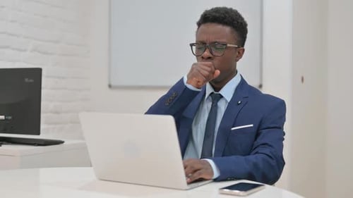 Young Adult Coughing While Working at Laptop