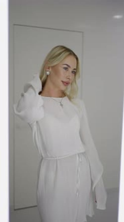 Attractive Woman Adjusts Hair in Mirror at Home