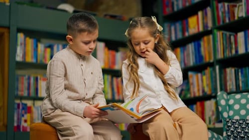 in Bookstore in the Children Area a Handsome Little Boy in Light Clothes and Girl Reads One Book