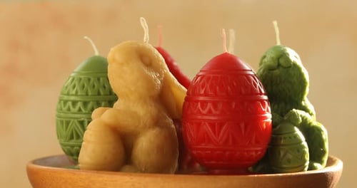 Beautiful candles on wooden tray against beige background, closeup. Easter decor