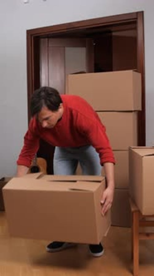 Man Carrying Cardboard Box in an Indoor Setting