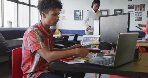 Biracial businessman working with laptop and holding photo at office