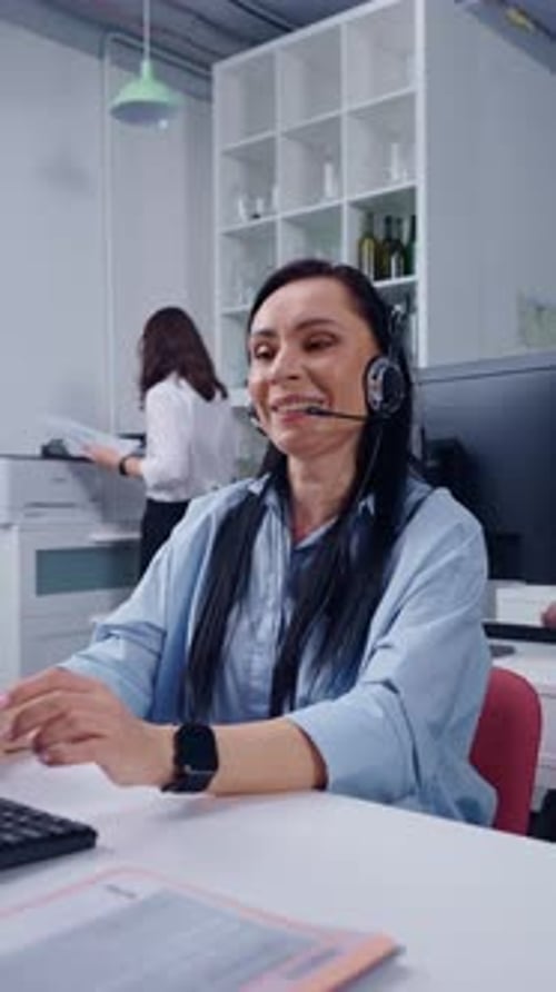 Focused Call Center Operator Wearing Headset Working at Computer in Modern Office Environment