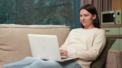 Woman Relaxes on Couch Using Laptop at Home