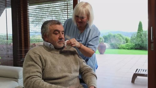 Woman Caregiver Assists Senior Man at Home