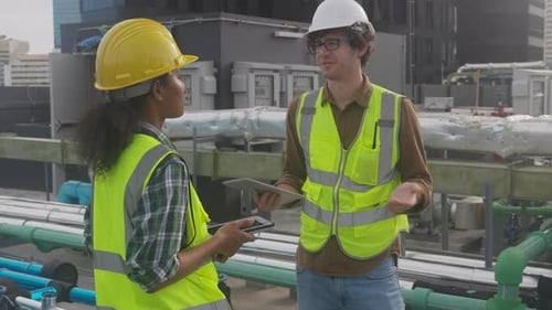 Young woman and man engineer walking and examining pipeline and looking digital tablet.