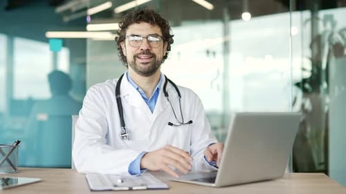 Doctor Smiling While Using Laptop in Modern Office