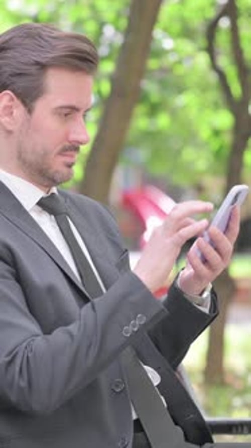 Professional Man Uses Smartphone in an Urban Park