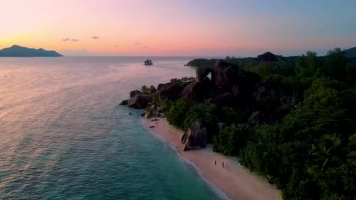 Pareja en la playa de Anse Source D'Argent durante la puesta de sol en Seychelles