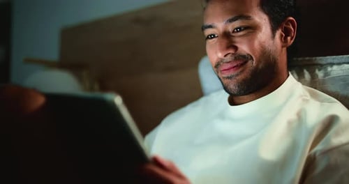 Man Using Tablet in Bed at Night