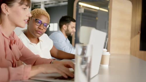 Collaborating on project, diverse colleagues discussing work and using laptops in office