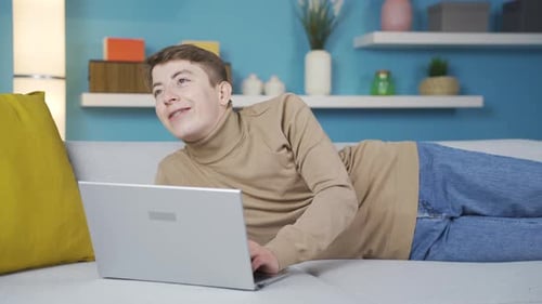 Young Man Using Laptop While Lying on Couch