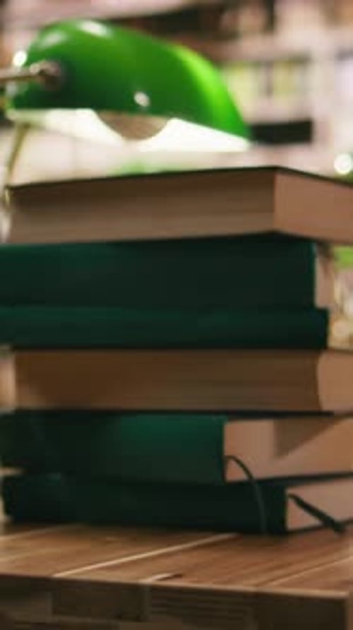 Vertical Video Stacked Green Hardcover Books on Desk in Empty Academic Library