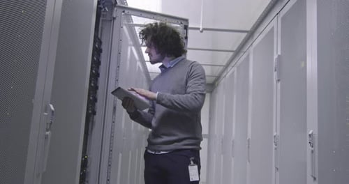 Man Working in Server Room with Tablet