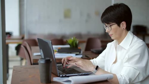 Attraktive reife Geschäftsfrau, die im Büro oder Coworking am Laptop arbeitet