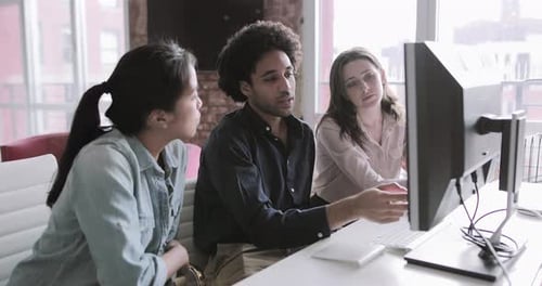 Mitarbeiter schauen gemeinsam auf einen Desktop-Computer