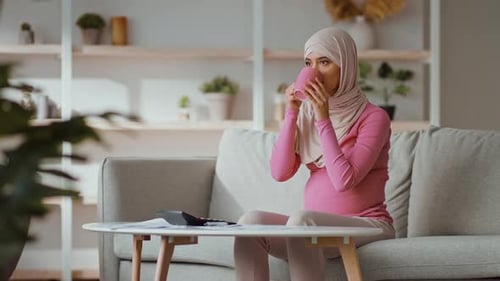 Pregnant Woman Drinking Coffee at Home on Couch