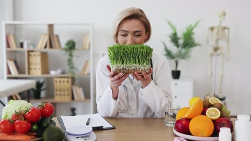 Smiling Woman Holding Microgreens in Bright Office