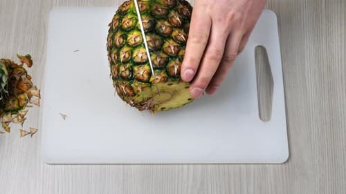 Pineapple Being Cut in Half on Cutting Board