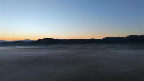 Sunrise Drone View with Low Fog Covering Landscape in Warm Morning Glow