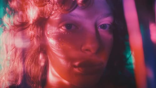 Portrait of Beautiful Girl with Glitter on Face in Multicolored Lighting
