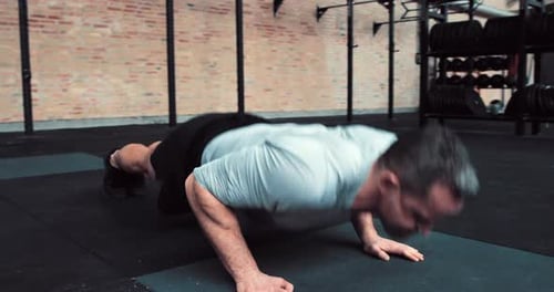 Determined man in sportswear doing pushups during strengthening workout at health club