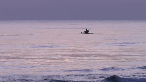 Sea kayak on calm sea at dawn, man paddling canoe at sunrise, mediterranean coast