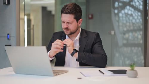 Frustrated Businessman with Headache Working on Laptop in Office