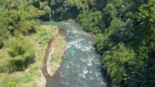 Drone camera following rafting boat float on winding rocky rapids river.