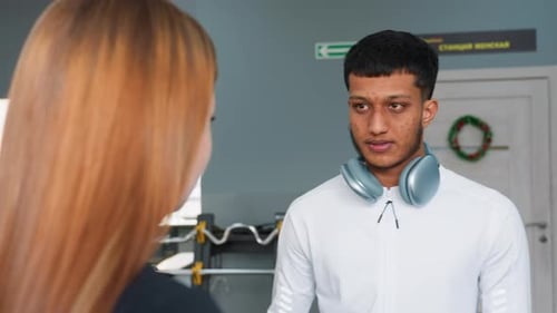 Woman Nods to Trainer Guidance As Man Walks Away in Gym
