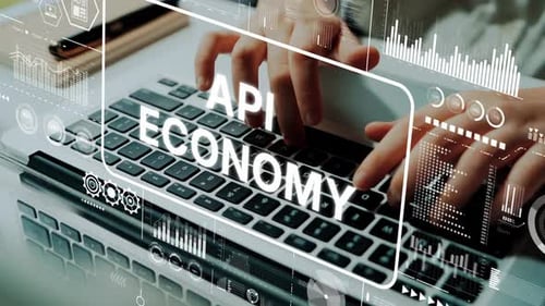 Tippen mit den Händen auf der Laptoptastatur mit API Economy-Textüberlagerung und digitalen Grafiken im modernen Arbeitsbereich