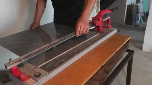 Man places gray tile on a cutting machine