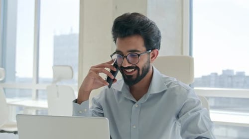 Happy Man Talking on Phone Working at Computer