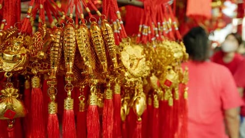 Close-up of golden ornaments with red tassels, with an out-of-focus person in red in the background