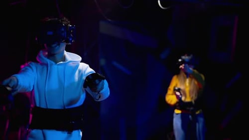 Group of people playing VR games in a studio with blue pink neon lights