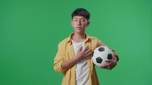 Man With Soccer Ball Stands In Front of Green