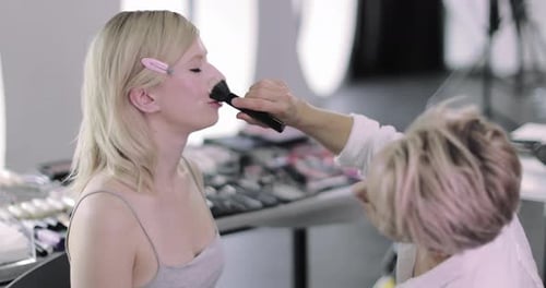 Woman Receives Makeup Application in Bright Studio