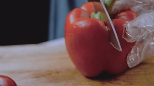 Front View of the Young Chef Cut Thin Slices of a Piece of Red Pepper with a Knife on the Cutting