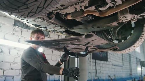 Car Mechanic Inspecting a Car in Auto Repair Shop