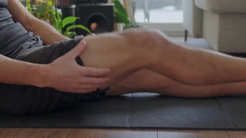 Man massaging leg muscles on yoga mat