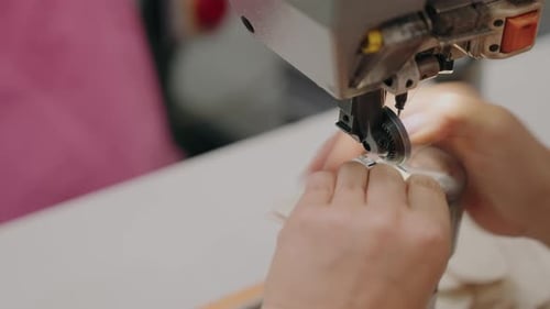 close up of hands sewing fabric with industrial sewing