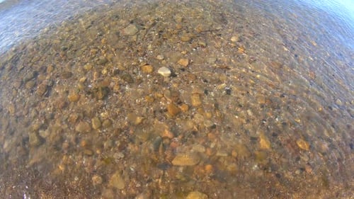 View Rocky Sandy Sea Bottom Through Clear Transparent Water with Waves Ripples