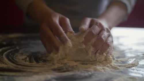 Frauenhände bereiten Pizzateig auf einem Marmortisch zu. Zeitlupe