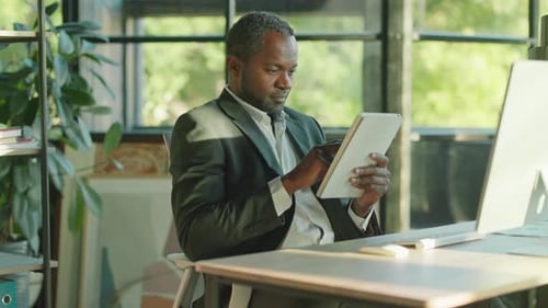 Man Using Tablet at Desk in Bright Office