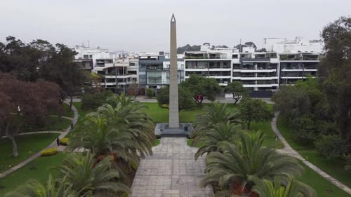 Vidéo d'un parc avec un obélisque avec un Drone 4K. Drone vole vers l'avant en direction de l'obélisque. Au-dessus d'une passerelle avec