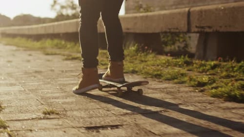Skateboarder Riding on Paved Sidewalk in Daytime