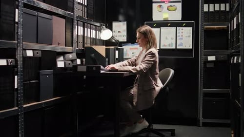 Woman Working At Desk In Office Surrounded By Files